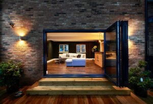 How Much Value Does a Garage Conversion Add? View into a garage conversion through bifold doors, what was once a double garage is now a large entertainment space with a sofa, bar and TV.